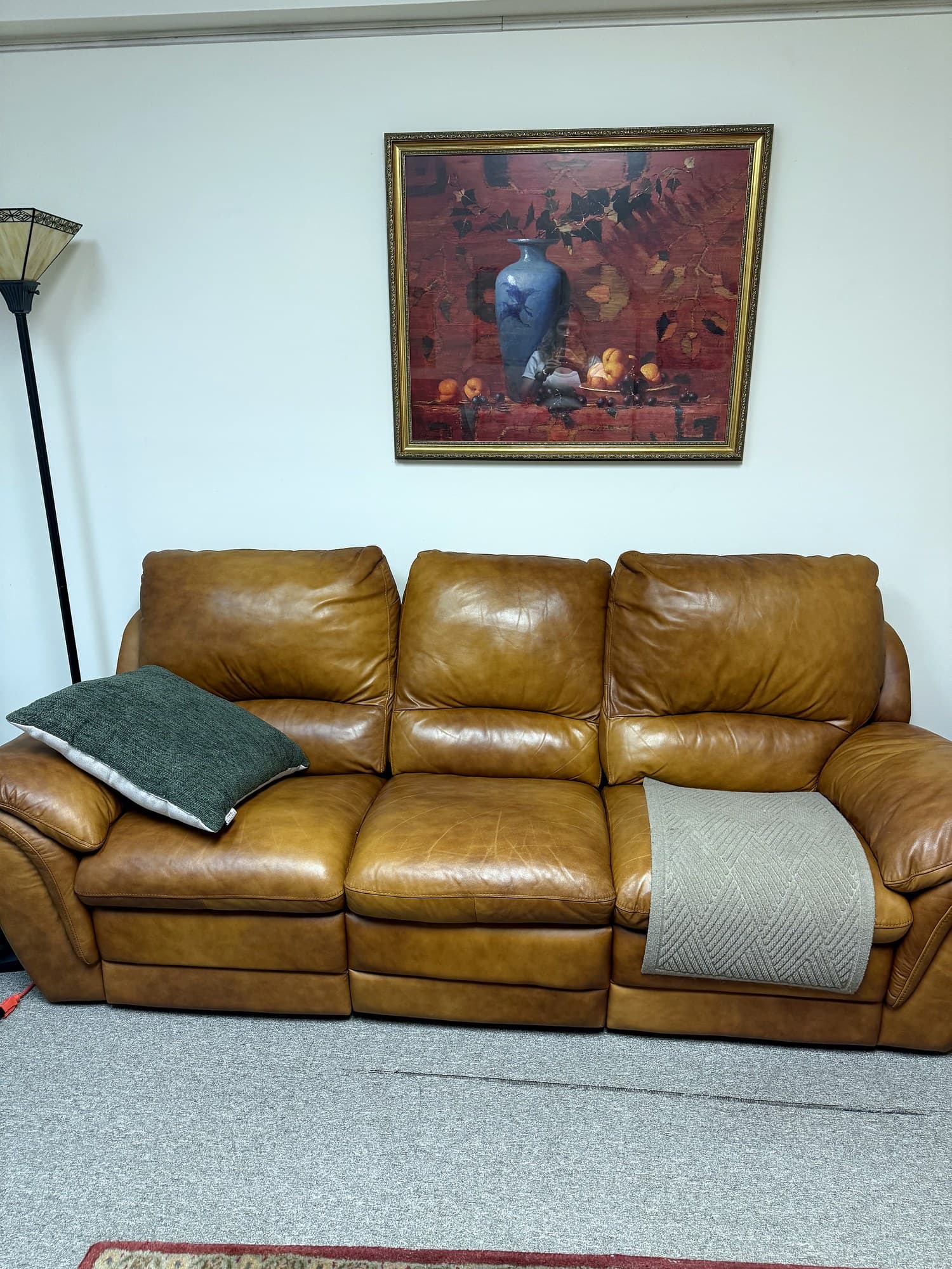 The session room — cognac leather sofa beneath a framed still-life
