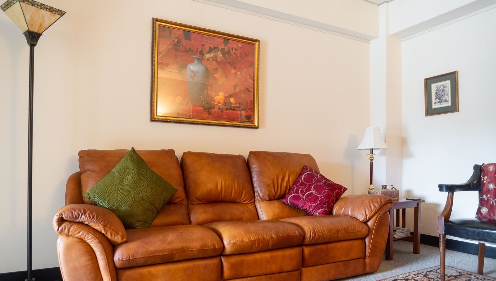 The session room in Elisabeth Coffey's Florham Park office — cognac sofa beneath a framed still-life